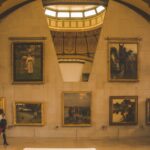 a group of people walking past paintings on a wall