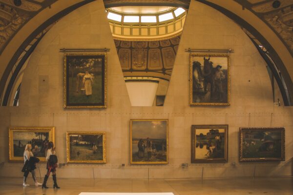 a group of people walking past paintings on a wall